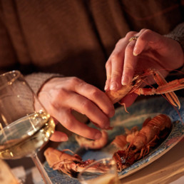 Person skalar bohuslänsk kräfta och dricker vitt vin.