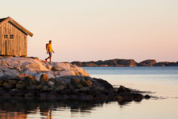 Man på klippor i den bohuslänska skärgården på västkusten i solnedgång.