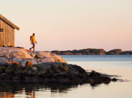 Man på klippor i den bohuslänska skärgården på västkusten i solnedgång.