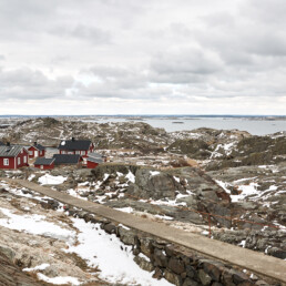 Bild på Ursholmens stugor på västkusten med snö på klipporna.