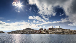 Röda stugor på klippor i solsken. Motljus.